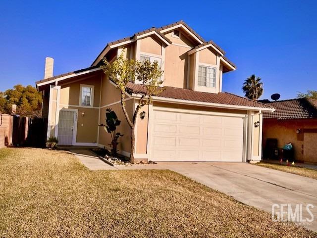 traditional-style house with a front yard, concrete driveway, a tile roof, and stucco siding