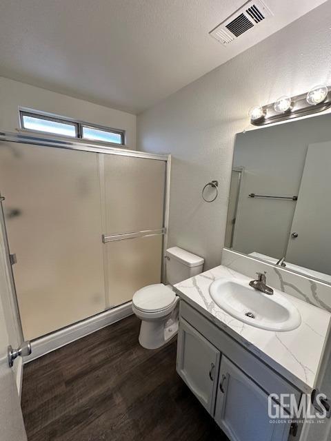 full bath featuring visible vents, toilet, wood finished floors, vanity, and a shower stall