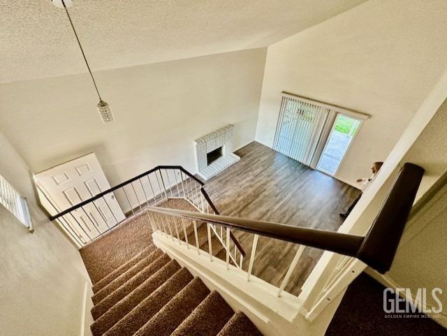 staircase featuring a textured ceiling, high vaulted ceiling, and wood finished floors