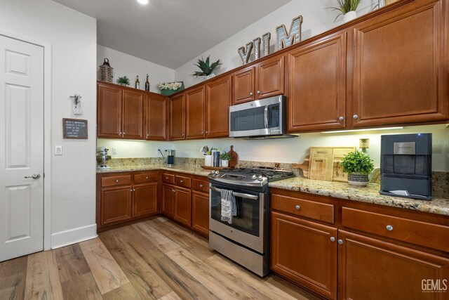 9700 Kingsport Pl, Bakersfield, CA 93306 - kitchen featuring stainless steel appliances, light wood-type flooring, light stone countertops, vaulted ceiling, and brown cabinetry