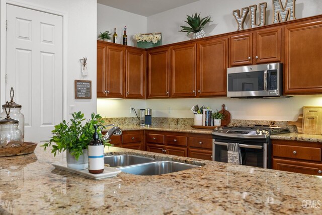 9700 Kingsport Pl, Bakersfield, CA 93306 - kitchen featuring appliances with stainless steel finishes, a sink, light stone counters, and brown cabinetry