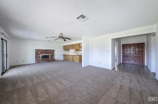 unfurnished living room featuring carpet flooring, ceiling fan, a textured ceiling, and a fireplace