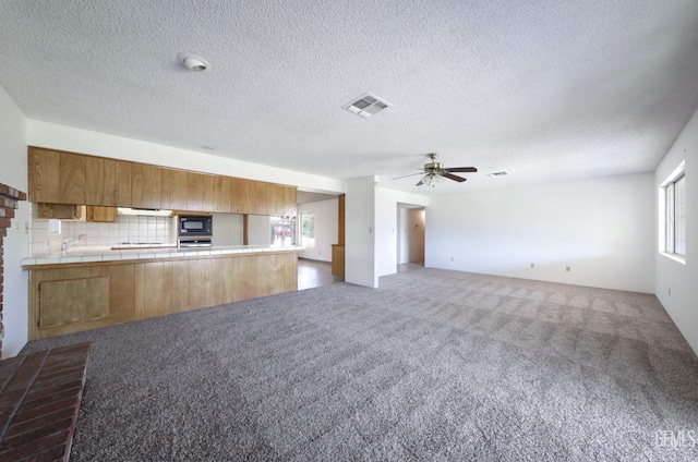 unfurnished living room with carpet flooring, ceiling fan, and a textured ceiling