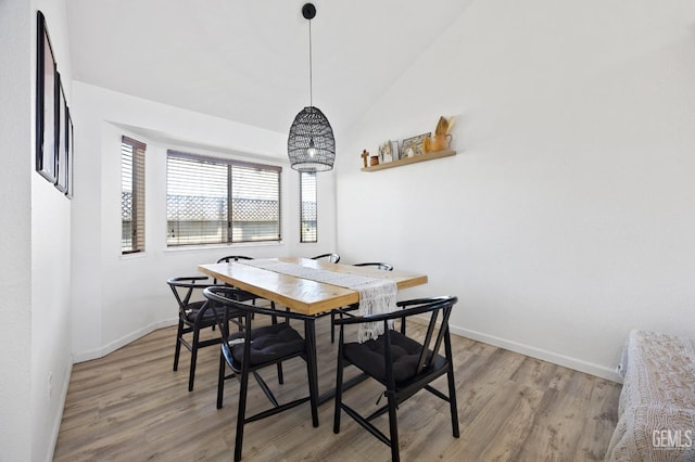 dining room with wood-type flooring and vaulted ceiling