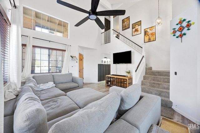 living room featuring wood-type flooring, ceiling fan, and a high ceiling