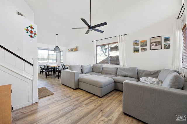 living room with ceiling fan, high vaulted ceiling, and light wood-type flooring