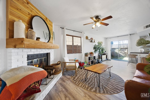 living room with hardwood / wood-style floors, a fireplace, and ceiling fan