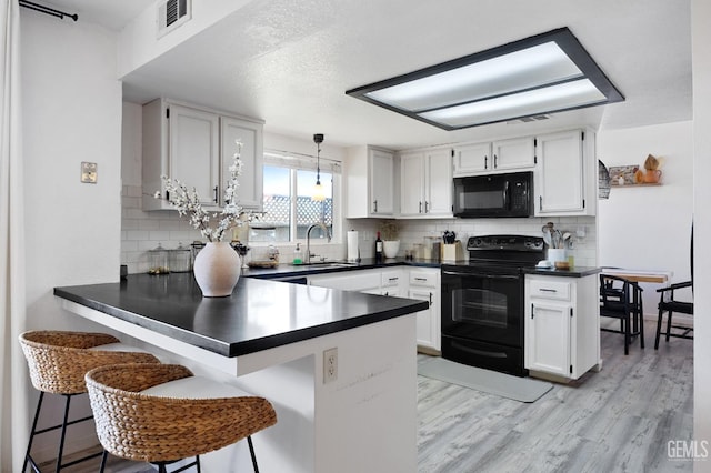 kitchen featuring white cabinetry, decorative light fixtures, kitchen peninsula, and black appliances