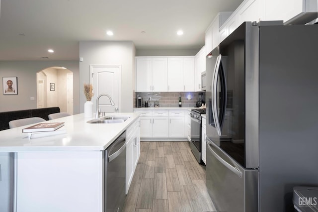 kitchen with white cabinetry, sink, stainless steel appliances, and an island with sink