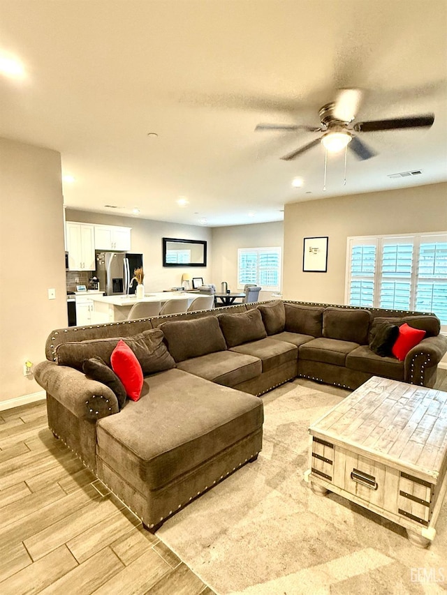 living room with light hardwood / wood-style floors and ceiling fan