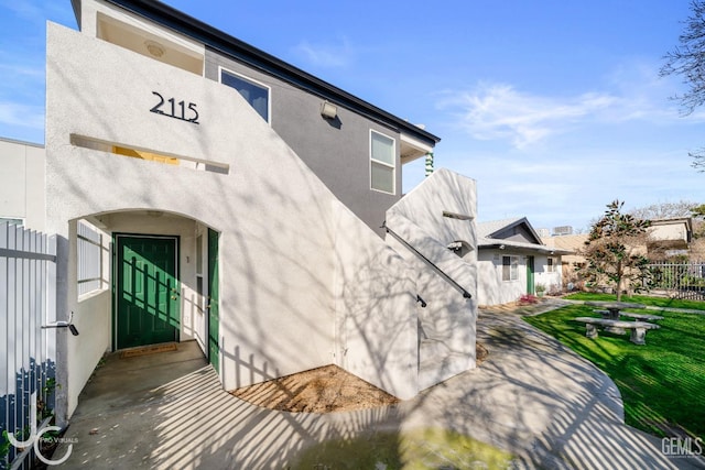 exterior space with a yard, fence, and stucco siding