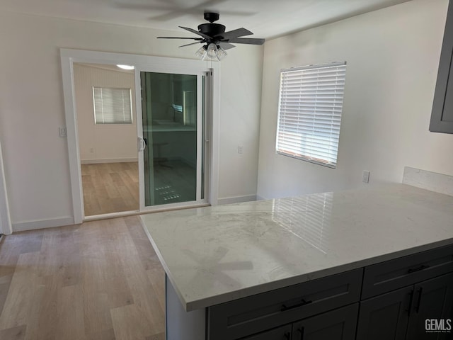 kitchen featuring light stone countertops, light hardwood / wood-style flooring, and ceiling fan