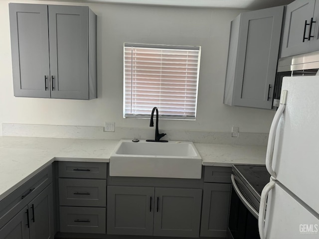 kitchen featuring gray cabinets, sink, and white fridge