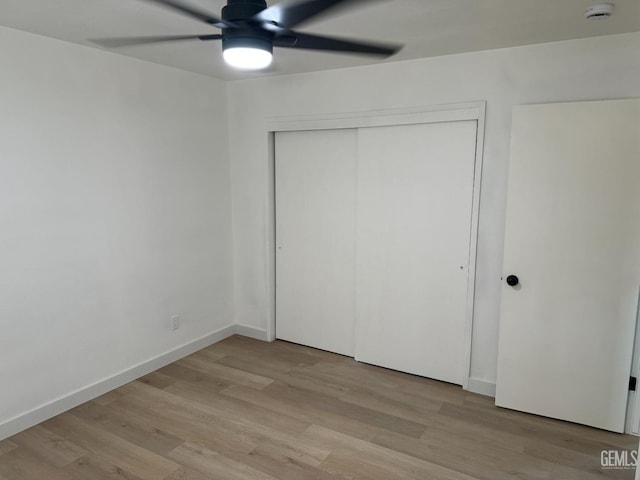 unfurnished bedroom featuring ceiling fan, light hardwood / wood-style floors, and a closet