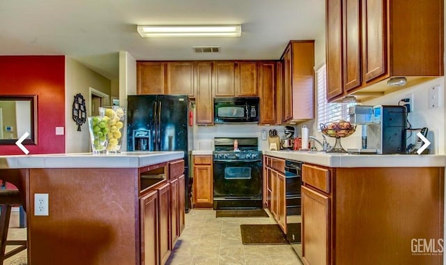 5429 White Wheat Ave, Bakersfield, CA 93313 - kitchen with black appliances, light countertops, a kitchen island, a breakfast bar, and brown cabinets