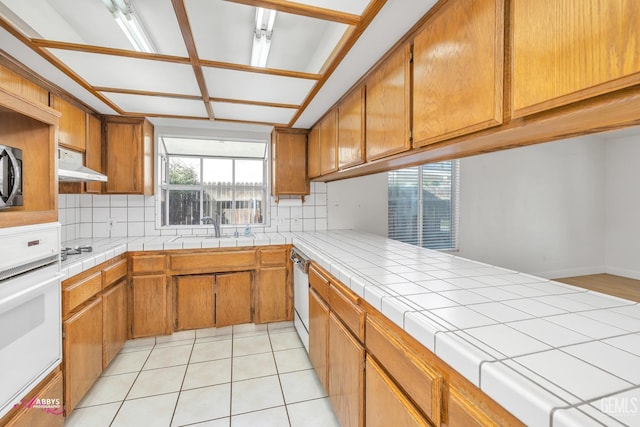 9812 Marilee Ave, Bakersfield, CA 93312 - kitchen featuring white oven, a sink, backsplash, dishwashing machine, and brown cabinetry