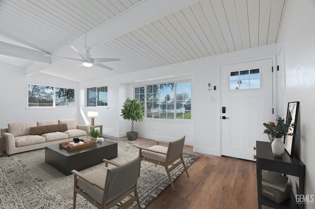 living area featuring vaulted ceiling with beams, dark wood-style flooring, plenty of natural light, and baseboards