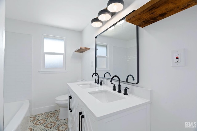 bathroom with baseboards, a sink, toilet, and double vanity