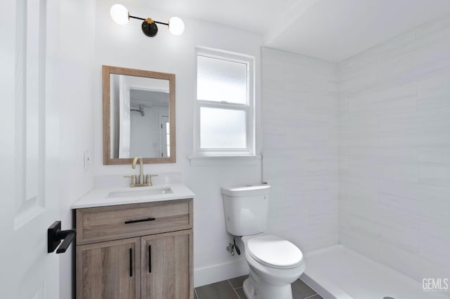 bathroom featuring toilet, baseboards, a tile shower, and vanity