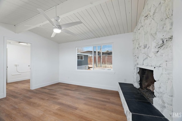 unfurnished living room with vaulted ceiling with beams, a fireplace, wood finished floors, wood ceiling, and baseboards