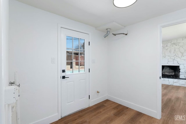 doorway with a fireplace, baseboards, and wood finished floors