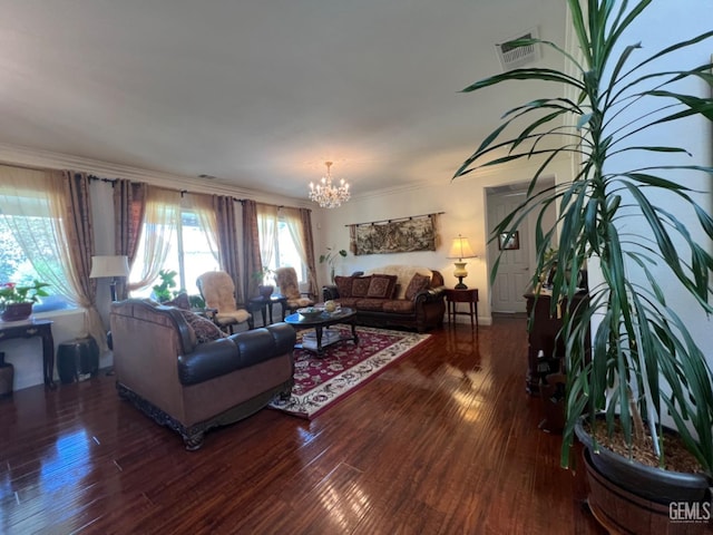 living room featuring dark hardwood / wood-style flooring, ornamental molding, and an inviting chandelier