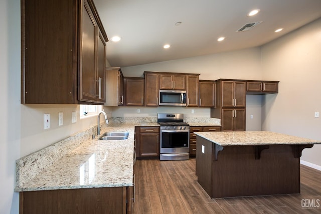 9029 Midnight Creek Way, Bakersfield, CA 93311 - kitchen with appliances with stainless steel finishes, dark wood-style flooring, a center island, lofted ceiling, and light stone counters