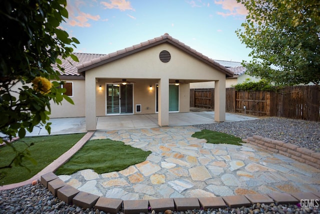 9029 Midnight Creek Way, Bakersfield, CA 93311 - back of property at dusk featuring ceiling fan, stucco siding, a fenced backyard, a patio area, and a tile roof