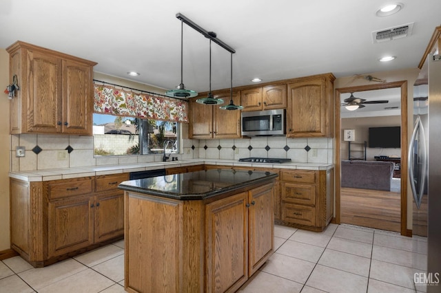 kitchen with appliances with stainless steel finishes, ceiling fan, sink, light tile patterned floors, and a kitchen island