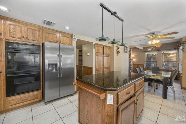 kitchen featuring ceiling fan, stainless steel fridge with ice dispenser, double oven, decorative light fixtures, and a kitchen island