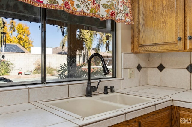 details featuring tasteful backsplash, tile counters, and sink