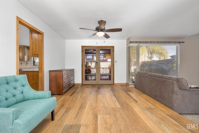 sitting room with french doors, light wood-type flooring, and ceiling fan