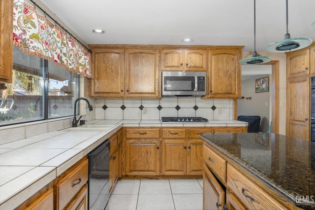 kitchen featuring decorative backsplash, stainless steel appliances, sink, light tile patterned floors, and hanging light fixtures