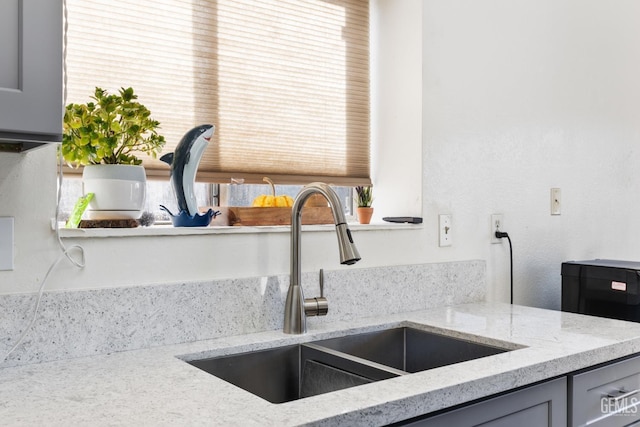 details featuring light stone counters, sink, and gray cabinets