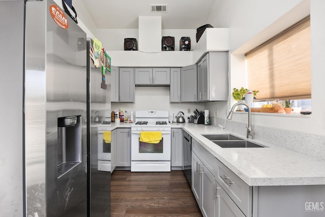 kitchen with dark hardwood / wood-style floors, sink, stainless steel fridge, white range with gas stovetop, and light stone countertops