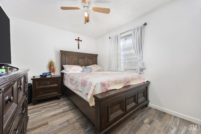 bedroom with ceiling fan, dark hardwood / wood-style flooring, and a textured ceiling