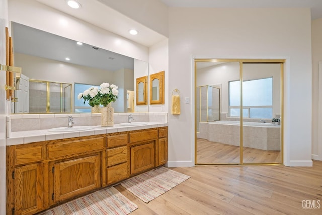 bathroom with hardwood / wood-style floors, vanity, and plus walk in shower