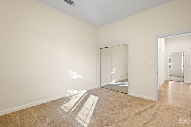 unfurnished bedroom with light carpet and a closet