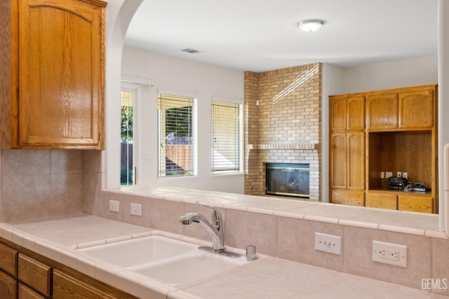 kitchen featuring tile counters, a fireplace, and sink