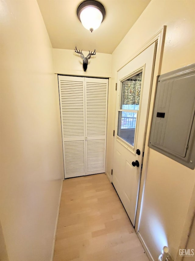 doorway to outside with light wood finished floors, electric panel, and baseboards