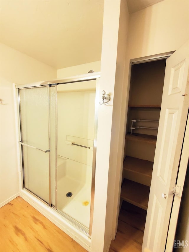 full bath with baseboards, wood finished floors, and a stall shower