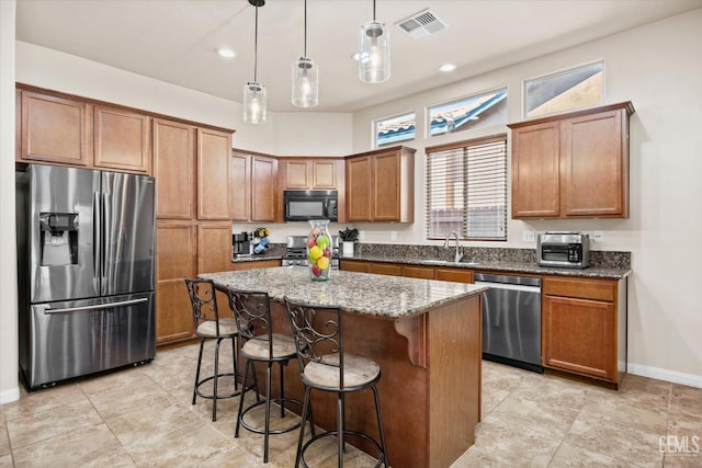 9510 Midnight Creek Way, Bakersfield, CA 93311 - kitchen featuring appliances with stainless steel finishes, dark stone countertops, a kitchen island, a kitchen breakfast bar, and hanging light fixtures