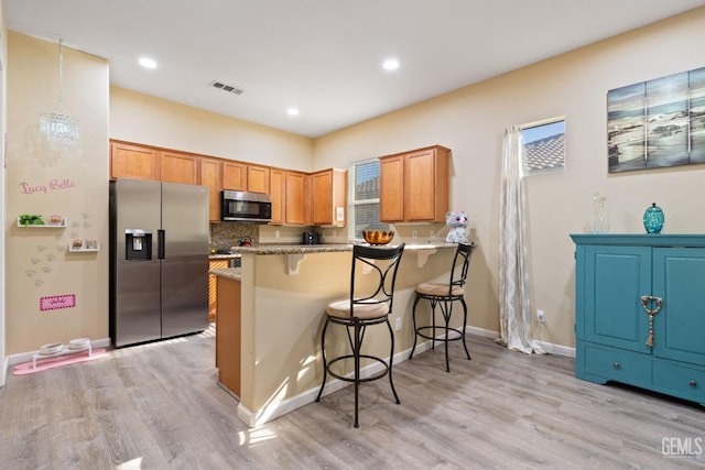 kitchen featuring tasteful backsplash, stainless steel fridge with ice dispenser, kitchen peninsula, light wood-type flooring, and a breakfast bar area