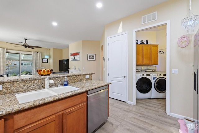 kitchen with washer and dryer, stainless steel dishwasher, light hardwood / wood-style flooring, light stone counters, and sink