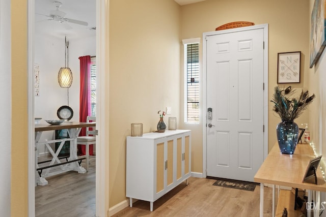 foyer featuring light wood-type flooring, ceiling fan, and a healthy amount of sunlight