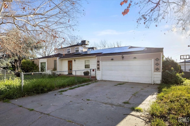 view of front of home featuring an attached garage, concrete driveway, solar panels, and fence