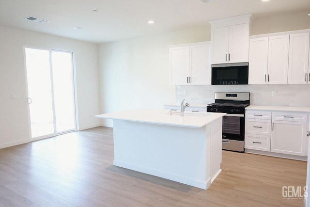 kitchen featuring light hardwood / wood-style flooring, decorative backsplash, an island with sink, white cabinets, and gas range