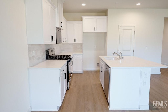 kitchen featuring stainless steel appliances, white cabinetry, sink, and an island with sink