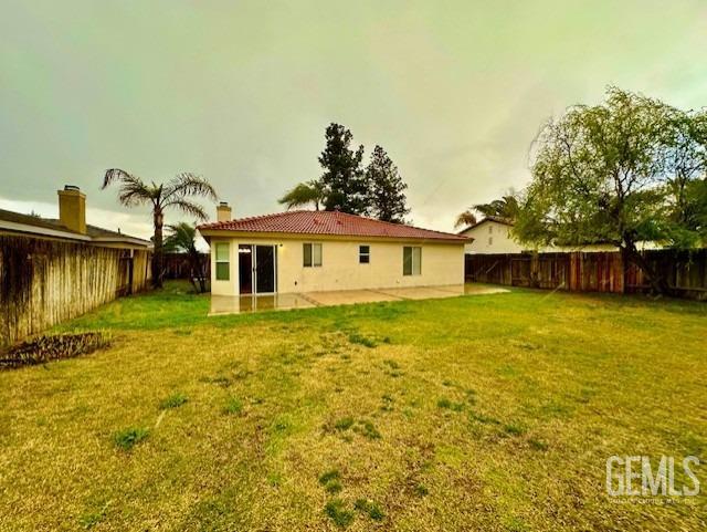 rear view of property featuring a yard, a patio, and a fenced backyard