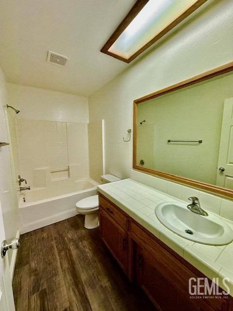 bathroom featuring vanity, wood finished floors, visible vents, shower / tub combination, and toilet